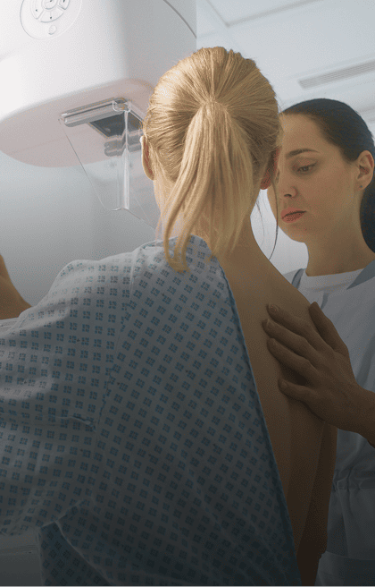 Médica realizando ultrassonografia de mamas em uma paciente de costas para a imagem